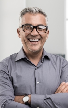 Smiling man in glasses and gray button up shirt