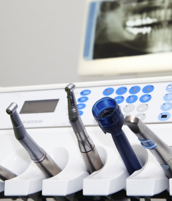 Several dental instruments on table with X ray of teeth in background