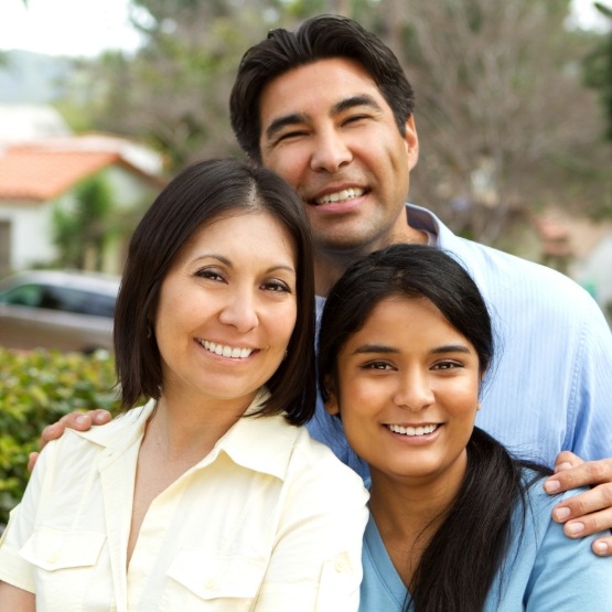 Family of three smiling outdoors