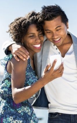 Smiling man and woman looking at phone together outdoors