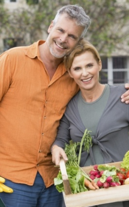 Smiling man and woman holding basket of fruits and vegetables