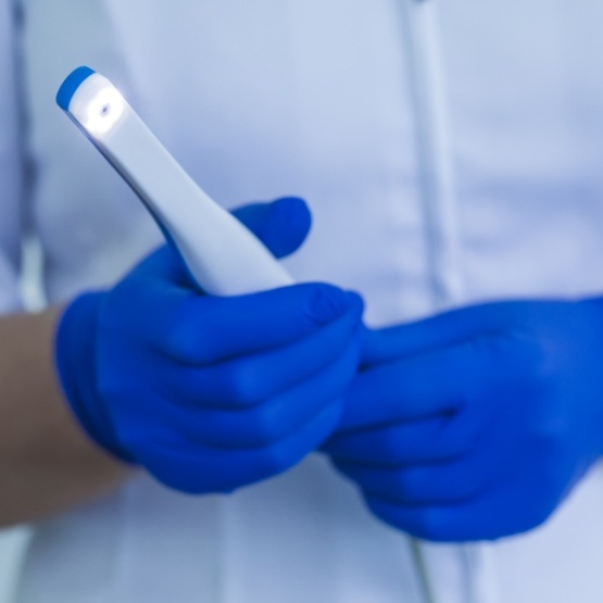 Gloved hands holding a thin white intraoral camera