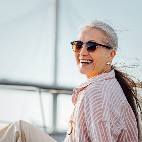 Senior woman with sunglasses sitting on boat and smiling