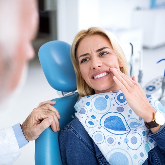 Woman wincing in pain while talking to dentist