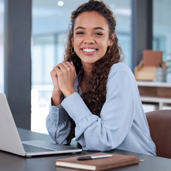 Woman sitting in front of laptop smiling