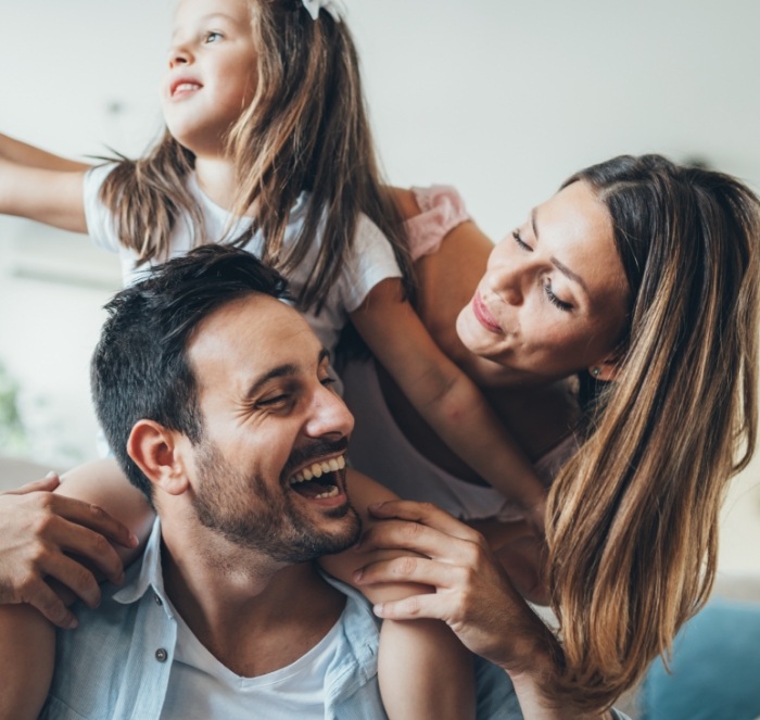 Family of three laughing on couch