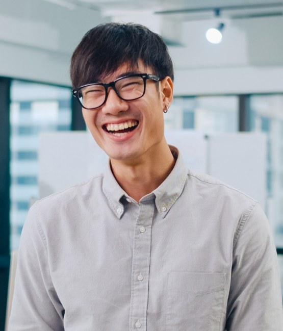 Young man with glasses smiling after preventive dentistry visit