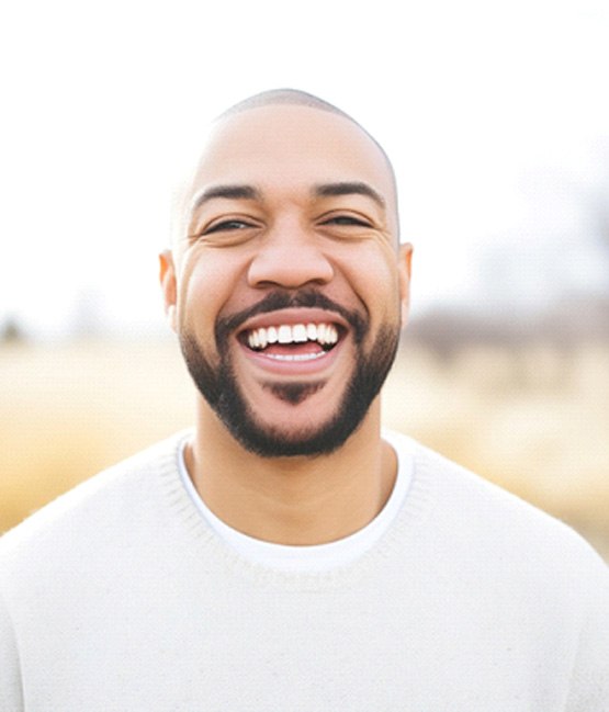 Man in white shirt smiling outside