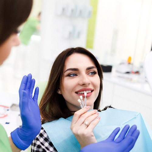 Smiling patient looking at different shades of porcelain
