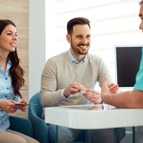 Dentist and couple talking in dental office