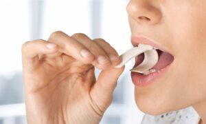 Nose to chin view of woman folding a piece of gum into her mouth