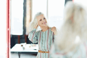 Woman adjusting her hair and smiling in the mirror