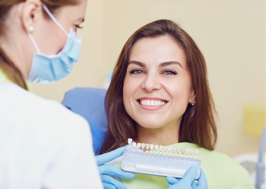 Patient comparing tooth shades during a professional teeth whitening consultation at a dental office
